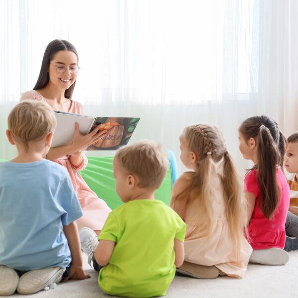 Nursery,Teacher,Reading,Story,To,Little,Children,In,Kindergarten